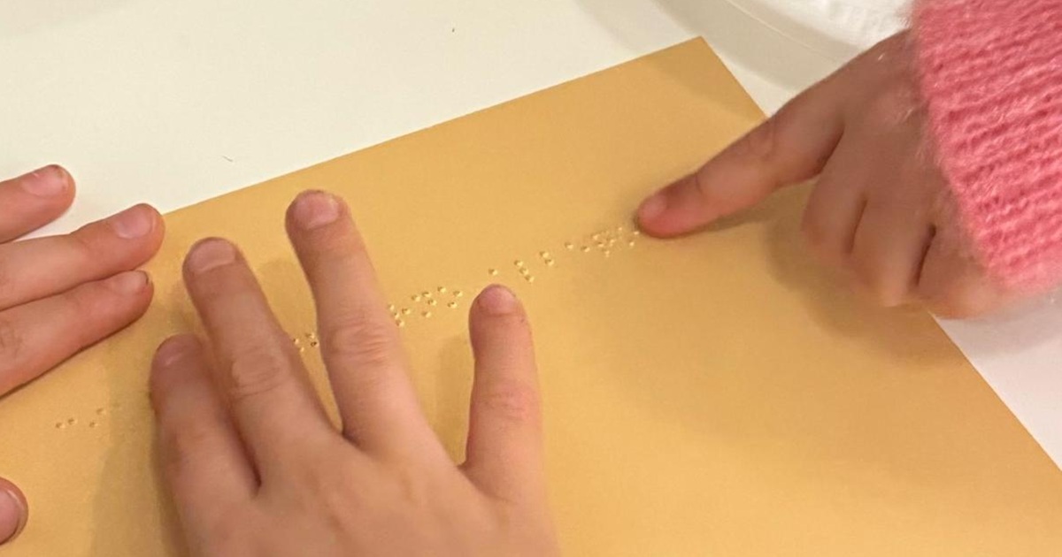 Dita di bambini su scritte in Braille